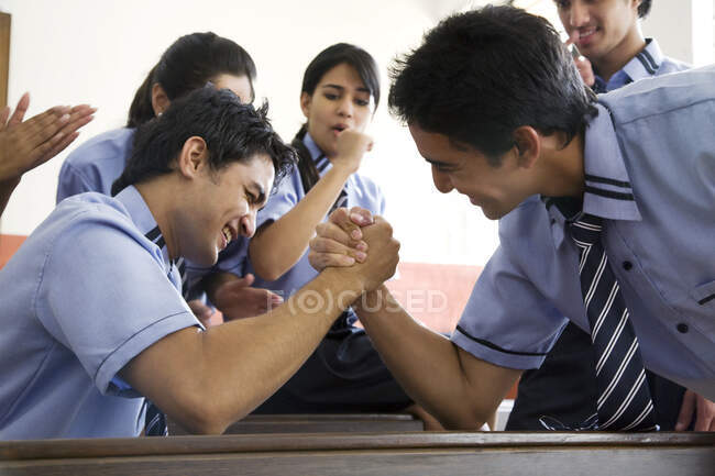 Boys arm wrestling in a classroom — Stock Photo