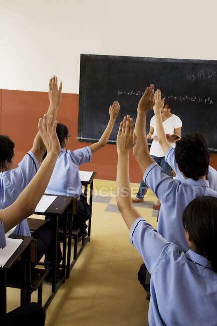 Studenti che alzano le mani in classe — Foto stock