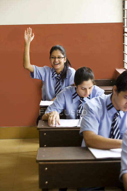 Menina levantando a mão em uma sala de aula — Fotografia de Stock