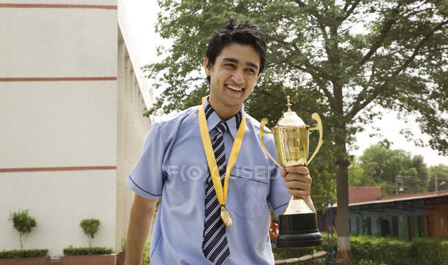 Student holding a trophy in the school yard — Stock Photo