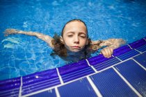 Ein nachdenkliches Mädchen entspannt sich am Rande eines Swimmingpools. — Stockfoto