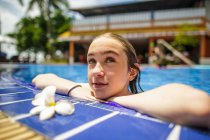 Ein nachdenkliches Mädchen entspannt sich am Rande eines Swimmingpools. — Stockfoto