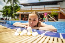 A thoughtful girl is relaxing by the side of a swimming pool. — Stock Photo
