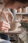 Gros plan d'une femme façonnant de l'argile sur une roue de poterie dans un atelier de céramique . — Photo de stock