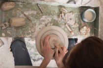 Ein Keramikkünstler, der in einer Keramikwerkstatt auf einer Töpferscheibe Ton formt. — Stockfoto