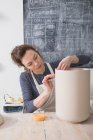 Un artista della ceramica sta mettendo i tocchi finali ad un'urna di ceramica in un laboratorio di ceramica . — Foto stock