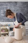 Um artista cerâmico está colocando os toques finais em uma urna de cerâmica em uma oficina de cerâmica . — Fotografia de Stock