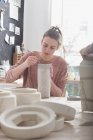 Um artista cerâmico está colocando os toques finais para um jarro de cerâmica em uma oficina de cerâmica . — Fotografia de Stock