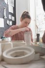 Un artista cerámico está dando los toques finales a una jarra de cerámica en un taller de cerámica . - foto de stock