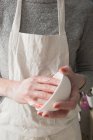 Uma artista de cerâmica está segurando uma tigela em suas mãos em uma oficina de cerâmica . — Fotografia de Stock