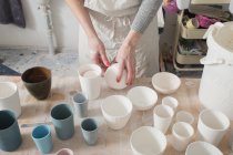 A ceramic artist is putting the finished ceramic products on the table in a pottery workshop. — Stock Photo