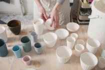 Ein Keramiker stellt die fertigen keramischen Produkte in einer Töpferei auf den Tisch. — Stockfoto