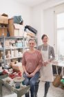 Two smiling ceramic artists portrayed in their pottery workshop. — Stock Photo