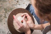 Close up of a woman's hand shaping pottery clay on a pottery wheel in a ceramic workshop. — Stock Photo