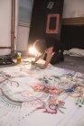 Kreativer männlicher Künstler arbeitet in seiner Werkstatt mit Papier auf dem Boden — Stockfoto