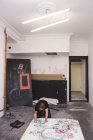 Творческий мужчина-художник, работающий в своей мастерской, стоя на коленях над бумагой — стоковое фото