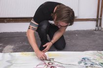 Kreativer männlicher Künstler in seiner Werkstatt beim Malen auf Papier — Stockfoto