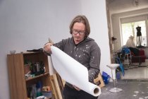Artiste masculin créatif travaillant dans son atelier et tenant du papier dans les mains — Photo de stock