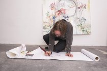 Творчий чоловік-художник працює на підлозі у своїй майстерні — стокове фото