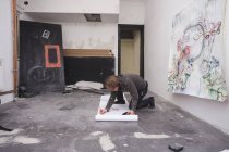 Творчий чоловік-художник працює на підлозі у своїй майстерні на підлозі — стокове фото
