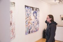Vista laterale di creativo artista maschile guardando la sua opera d'arte in una galleria d'arte . — Foto stock