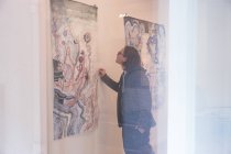 Креативний художник-чоловік дивиться свої твори мистецтва на стіні в художній галереї . — стокове фото