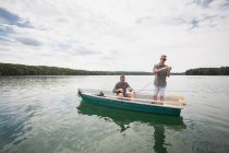 Due uomini caucasici stanno preparando la loro attrezzatura per la pesca a mosca da una barca sul lago . — Foto stock