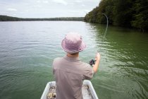 Задний вид человека - рыбалка с лодки на озере . — стоковое фото