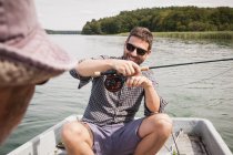 Caucasian men are fly fishing in boat on lake. — Stock Photo