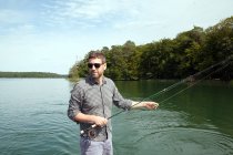 Un hombre es la pesca con mosca desde el barco en el lago . - foto de stock
