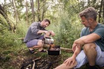 Due uomini stanno preparando la griglia per un barbecue in natura aperta . — Foto stock