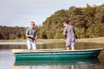 Los hombres caucásicos son la pesca con mosca en barco en el lago . - foto de stock