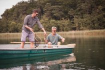 Caucasian men are fly fishing in boat on lake water — Stock Photo