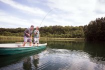 Caucasian men are fly fishing in boat on a lake. — Stock Photo