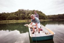 Two fly fishers are setting free a pike into the freshwater after catching it. — Stock Photo