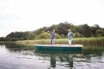 Caucasian men are fly fishing in boat on lake during daytime — Stock Photo