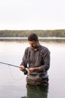 Un homme en échassier pêche à la mouche dans un lac . — Photo de stock