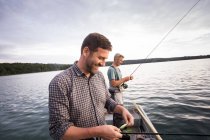 Caucasian men are fly fishing in boat on lake. — Stock Photo