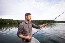 Side view of man is fly fishing from a boat on lake. — Stock Photo