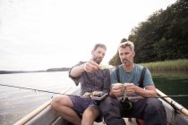 Due uomini stanno raccogliendo una mosca da pesca a mosca affrontare in barca sul fiume . — Foto stock