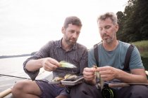 Deux hommes ramassent une mouche de pêche d'un attirail de pêche à la mouche en bateau sur la rivière . — Photo de stock