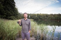 Vista frontal do pescador de mosca caucasiano com sua vara de pesca em um lago . — Fotografia de Stock