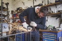 Un forgeron porte un équipement de sécurité et utilise une meuleuse sur une construction métallique dans un atelier de métallurgie
. — Photo de stock