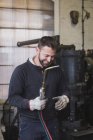 Ein lächelnder Schmied benutzt in seiner Werkstatt ein Schneidbrenner. — Stockfoto