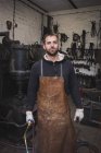 Ein Schmied in Lederschürze und mit Schneidbrenner in seiner Werkstatt. — Stockfoto