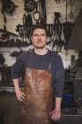 A blacksmith wears a leather apron and is portrayed in his workshop. — Stock Photo