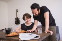 Ein junges Paar checkt am Frühstückstisch mit dem Smartphone soziale Medien. — Stockfoto