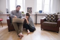 Ein junges Paar surft im Internet, während es sich im Wohnzimmer entspannt. — Stockfoto