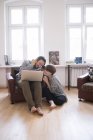 A young couple is listening to music from a computer in the living room. — Stock Photo