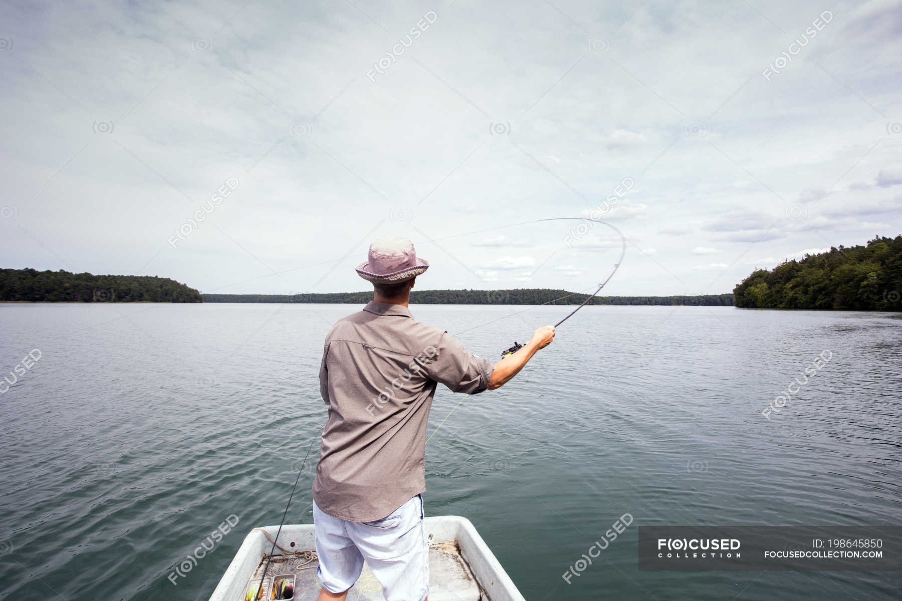 A man is fly fishing from a boat on lake. — daylight, transport Stock